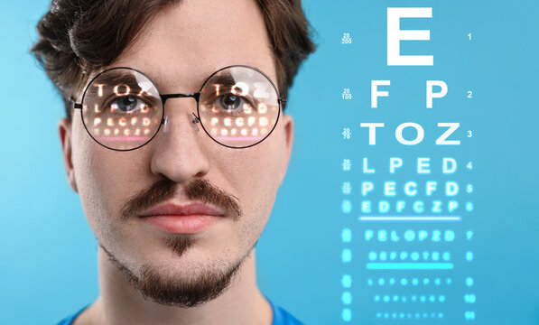 Man in glasses and eye chart on blue background, selective focus. Vision check