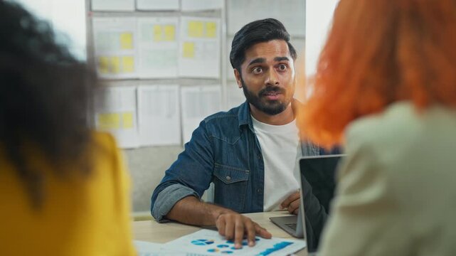 Diverse multiracial team planning new business strategy with AI marketing consultant on multiple screens and documents in modern open office, corporate restructuring and transformation concept