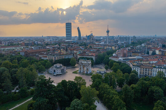 Aerial view of Parco Sempione and the Arco della Pace surrounded by lush greenery and the modern skyline of Milan, Lombardy, Italy.