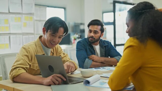 Diverse multiracial team planning new business strategy with AI marketing consultant on multiple screens and documents in modern open office, corporate restructuring and transformation concept