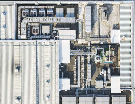 Aerial view of industrial rooftop featuring rows of ventilation ducts and air conditioning units on a corrugated metal surface in Taiwan.