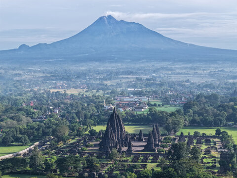 Aerial view of Prambanan Temple with stone spires and lush greenery, with Mount Merapi volcano in the background in Kecamatan Prambanan, Daerah Istimewa Yogya, Indonesia.