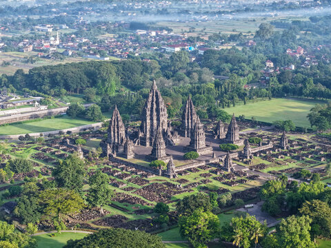Aerial view of Prambanan Temple featuring iconic towering spires and archaeological ruins set amidst lush green gardens in Kecamatan Prambanan, Daerah Istimewa Yogya, Indonesia.