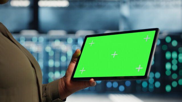 Data center technician uses green screen tablet in a data center to inspect hardware and maintain system stability.