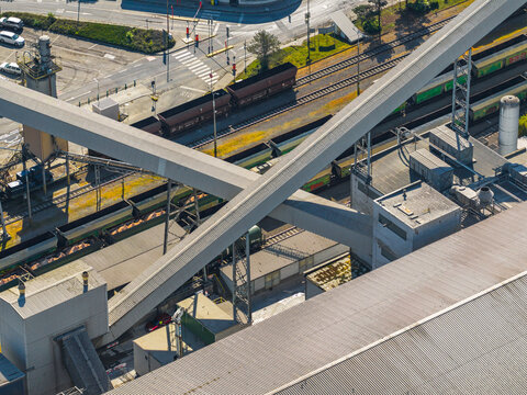 Aerial view of an industrial area with large conveyor belts crossing over railway tracks and freight trains in Prague, Prague, Czechia.