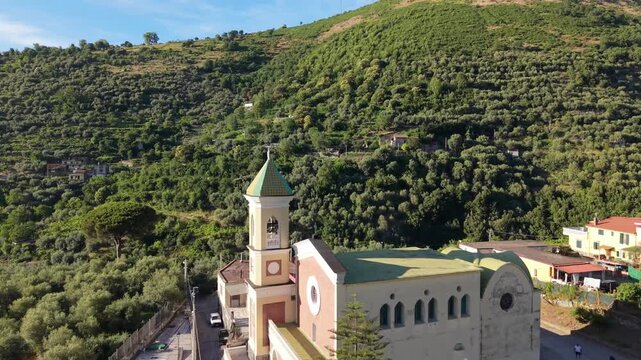 Aerial view of Chiesa di Sant'Agnello Abate church with bell tower surrounded by terraced olive groves on hillside in Gragnano, Naples, Italy
