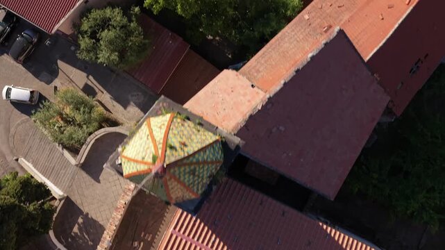 Aerial top view of Parrocchia Sant'Agnello Abate church rooftop with colorful tiled dome, terracotta roof and courtyard with trees in Aurano, Gragnano, Naples, Italy
