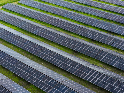 Aerial view of rows of photovoltaic solar panels installed on a green field in Suntazi, Ogre Municipality, Latvia.