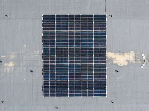 Aerial view of a solar panel array installed on a flat grey roof in Malpils, Sigulda Municipality, Latvia.