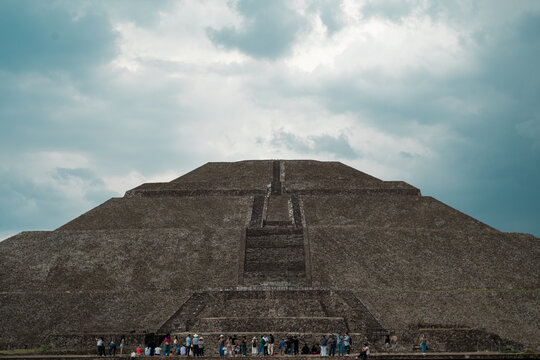 Vista Frontal de la Pir&aacute;mide del Sol de Teotihuacan desde Abajo con Turistas en la Base y Cielo Nublado