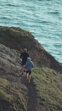 Hiking friends coastline two men walking along a scenic cliff path overlooking the turquoise sea during a bright day