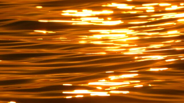 Water reflection golden rippling waves surface background texture shimmering during sunset light creating peaceful atmospheric mood for cinematic b roll footage project