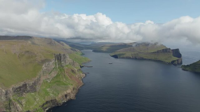 Scenic aerial view of giant cliffs over the ocean where the Postman&rsquo;s trail leads to the tiny village G&aacute;sadalur with its famous waterfall M&uacute;lafossur on the Faroe Islands.