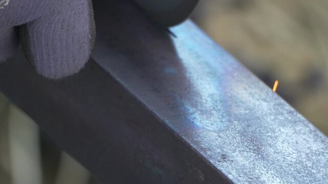 Grinding, metal, industrial workshop cutting thick steel bar with angle grinder tool creating bright flying sparks in slow motion