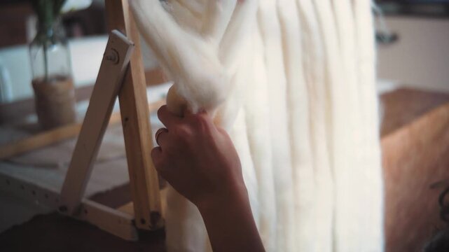 A young woman making a macram&eacute; tapestry out of wool 
