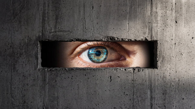 Conceptual Shot of Mass Surveillance and Data Privacy with Human Eye Behind Concrete Slit