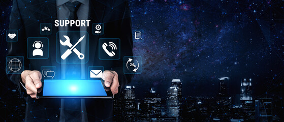 Fototapeta premium Professional business person in a suit holds tablet displaying support icons against a night city skyline with stars and cosmic background. Glyphic.