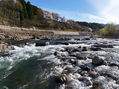 Rushing river flows over rocky bed with white froth