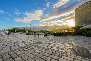 Fototapeta premium Sunset sky above sidewalk cafes and marinas at the seaside promenade of Rovinj, Croatia, on the Istrian Peninsula of the Adriatic Sea.