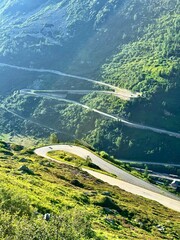 Naklejka premium Winding hairpin mountain pass road snaking down lush green alpine