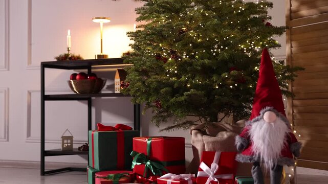 Beautiful Christmas tree with twinkling lights, gift boxes and other festive decor indoors