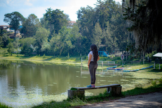 mujer a la orilla de un lago verde 