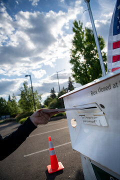 Vertical election image showing a voter using an official ballot drop box. Useful for election coverage, civic engagement campaigns, government communications, and voter outreach materials.