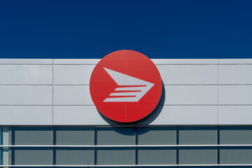 Obraz premium Toronto, Canada - June 27, 2026: Closeup red circular logo of Canada Post displayed on the exterior of a Canada Post facility in Toronto, Canada. Canada Post operates as a federal Crown corporation. 