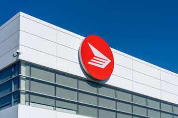 Fototapeta premium Toronto, Canada - June 27, 2026: Closeup red circular logo of Canada Post displayed on the exterior of a Canada Post facility in Toronto, Canada. Canada Post operates as a federal Crown corporation. 