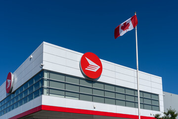 Fototapeta premium Toronto, Canada - June 27, 2026: Flag of Canada and Canada Post logo displayed on the building in Toronto. Canada Post operates as a federal Crown corporation.