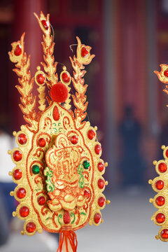Ornate golden amulet with red and green jewels, symbolizing good fortune