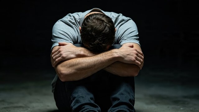 Depressed man sitting alone in darkness, head in hands, emotional pain, mental health struggle, loneliness, sadness, despair, psychological crisis
