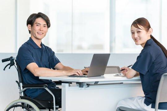 A male staff member in a wheelchair working at a desk in the office.