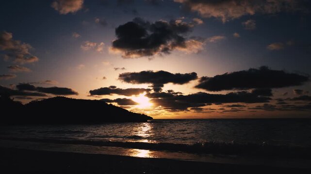 朝日に照らされる美しい波打ち際とシルエットの島影（スローモーション）