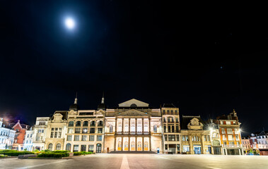 Naklejka premium The illuminated facade of Theater Jean Vilar on a clear night under a full moon in the historic center of Saint-Quentin, France.