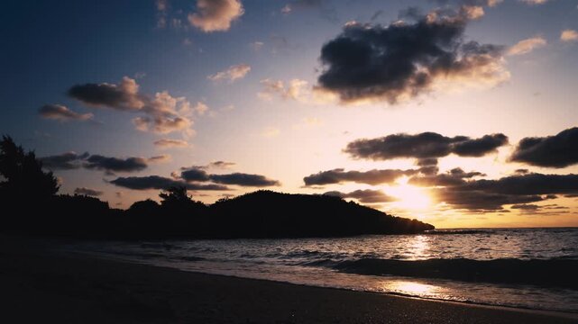 朝日に照らされる美しい波打ち際とシルエットの島影（スローモーション）