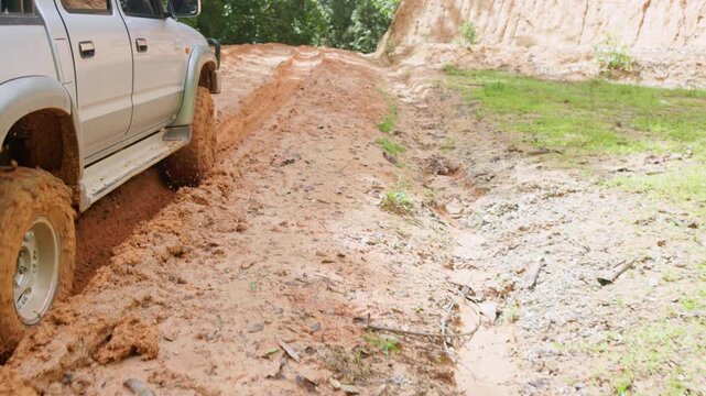 Close up of 4x4 SUV tire spinning in deep mud with heavy splash. Cinematic 4K slowmo video showing engine power and wheel traction.