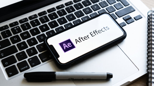 Adobe After Effects logo displayed on a smartphone screen placed on a silver laptop keyboard