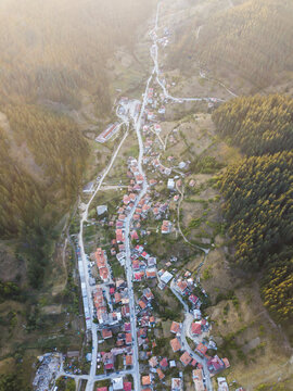 Aerial view of the town nestled in a lush mountain valley with winding roads and dense pine forests in Chepelare, Smoljan, Bulgaria.