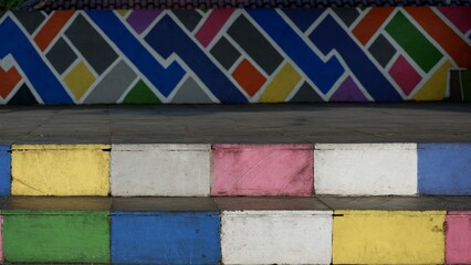 Colorful concrete steps and a painted geometric mural wall backdrop featuring vibrant abstract street art patterns. © agung