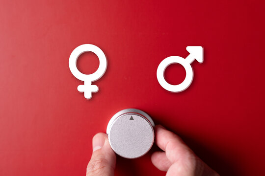 A hand adjusts a dial between male and female symbols on a red background, symbolizing a choice between genders.