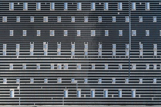 Aerial view of a large logistics warehouse roof covered with solar panels and numerous skylights in Kunice, Central Bohemian Region, Czechia.