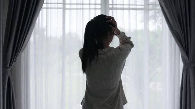 4K silhouette of sad depressed woman sitting alone in dark room. Concept of mental health, anxiety and female relation problems.