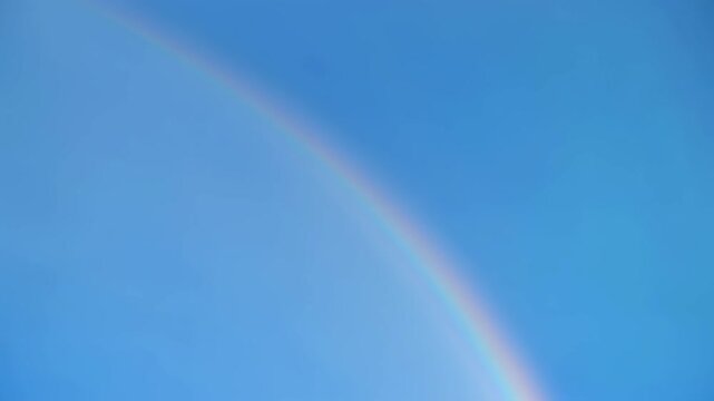 Vibrant rainbow arc across clear blue sky