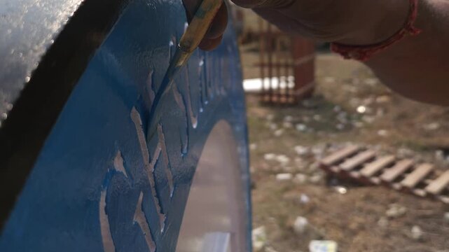 Authentic footage of an Indian stone sculpture artist hand-painting a Platinum Jubilee commemorative school logo sculpture in Odisha, India. The video showcases traditional craftsmanship