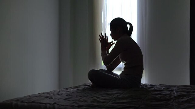 4K footage of anxious depressed woman staring in gloomy room. Silhouette of female dealing with grief, stress and healing journey.