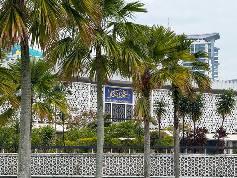 Kuala Lumpur, Malaysia - April 15, 2026: Masjid Negara National Mosque exterior with palm trees and Islamic lattice fence