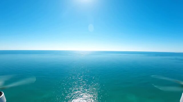Aerial drone view of a perfectly calm turquoise ocean meeting a crisp horizon line against a bright cloudless sky