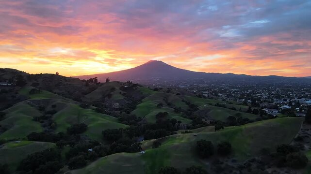 Cinematic aerial drone flight over the lush green Dougherty Hills in San Ramon with a breathtaking sunset view of Mount Diablo