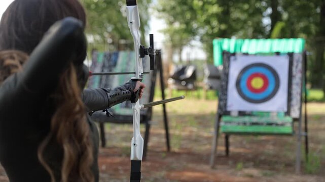 Woman archer aiming and shooting arrow at target